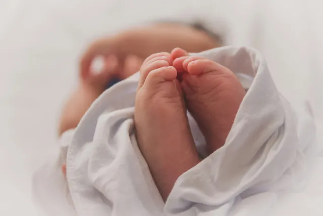Close-up of a newborn's bare feet peeking out of a white blanket